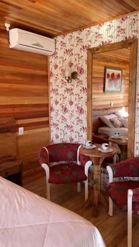 a bedroom with a bed and a table and chairs at Cabanas Por do Sol in Urubici