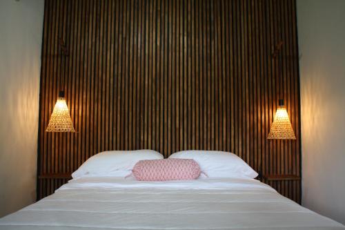 a bed with two lamps and a pink pillow on it at Hotel Daleese in Uvita