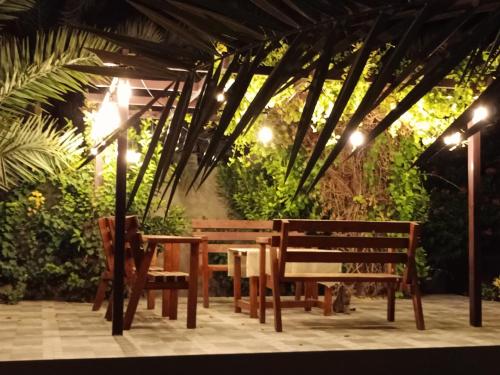 a table and two benches and a table and chairs at استراحة شرفة الواحةOasis Terrace Inn and Lounge in Bahlāʼ