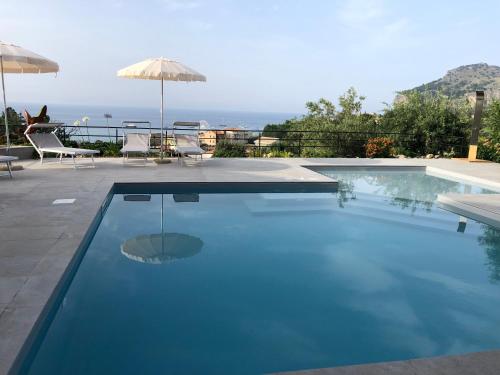 a swimming pool with two chairs and an umbrella at Casa Miraflores in Cefalù