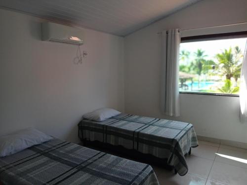 a bedroom with two beds and a large window at Bangalô 7b Praia de Guaratiba in Prado