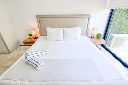 a bedroom with a large white bed and a window at OP downtown Studio by Casago in Playa del Carmen