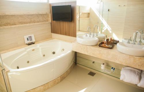 a bathroom with two sinks and a tub and a mirror at Itaimbé Palace Hotel in Santa Maria