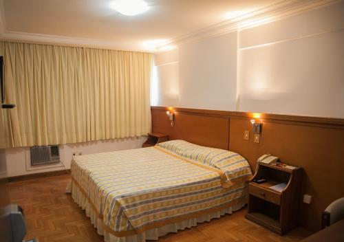 a hotel room with a bed and a telephone at Itaimbé Palace Hotel in Santa Maria