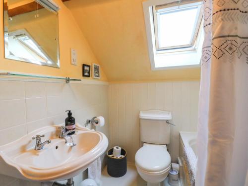 a bathroom with a sink and a toilet and a window at Granary Cottage in Oasby