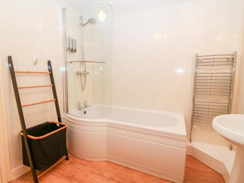 a bathroom with a shower and a tub and a sink at Oak Cottage in Caernarfon