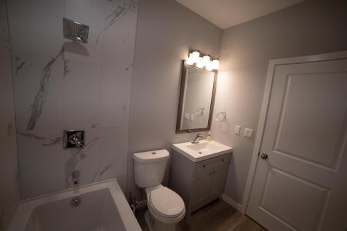 a bathroom with a toilet and a sink and a mirror at Kid & Pet Friendly Walkout BSMT 90 mins to Banff and 30 mins to Downtown Calgary in Calgary