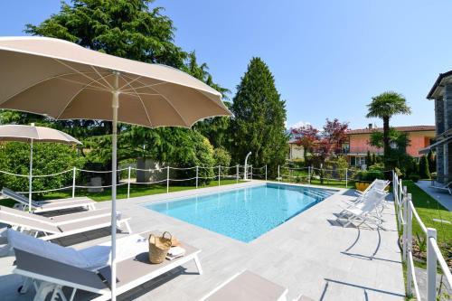 a swimming pool with chairs and an umbrella at Regina e Oriente in Baveno