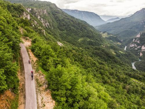 a person riding a bike down a road in a valley at GRAB ethno village and camp in Šćepan-Polje