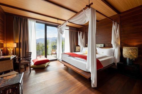 a bedroom with a canopy bed with a large window at Manna Resort in Montagna