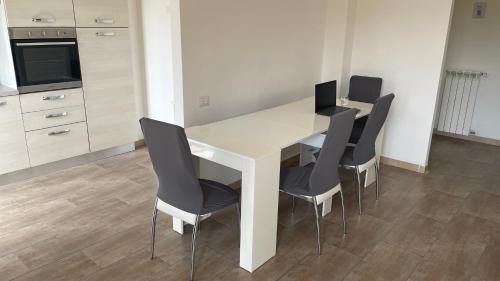 a kitchen with a white table and black chairs at Lux Kuoni Grace - Appartamento a due passi dal porto in Civitavecchia