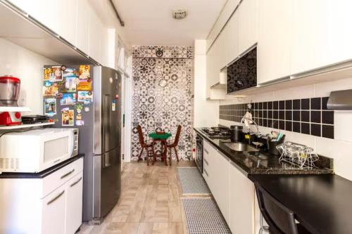 a kitchen with black counter tops and a refrigerator at Quarto em casa de vila em Botafogo, Rio de Janeiro in Rio de Janeiro