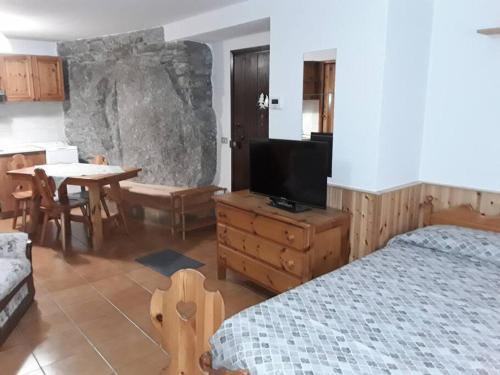 Schlafzimmer mit einem Bett, einem TV und einem Tisch in der Unterkunft Tana della volpe 2 in Gressan