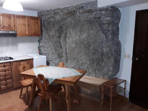 a kitchen with a wooden table and a stone wall at Tana della volpe 2 in Gressan