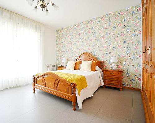 1 dormitorio con cama de madera y papel pintado con motivos florales en A Casa de Otilia, en Meaño