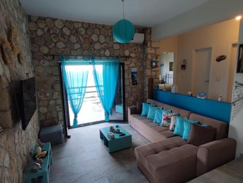 sala de estar con sofá marrón y pared de piedra en Korina's house, en Loutsa