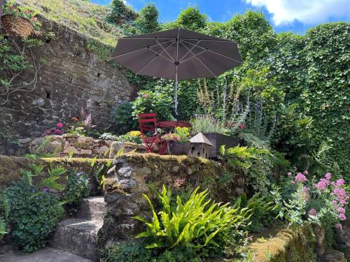 um jardim com uma cadeira e um guarda-sol em Maison Médiévale em Dinan