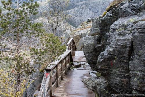 a wooden bridge over a canyon with a mountain at 14 B in Stavanger