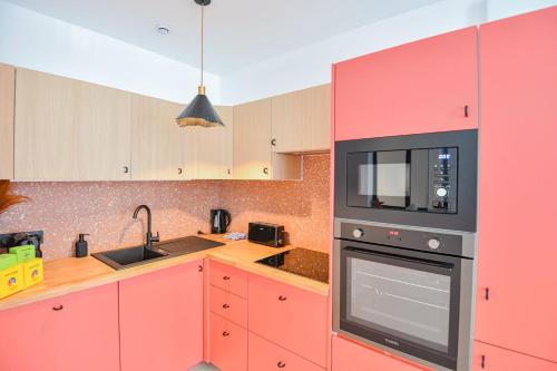 - une cuisine avec des placards rouges et un four micro-ondes noir dans l'établissement Appart 2 ch clim proche Vieux-Port Gare St-Charles, à Marseille