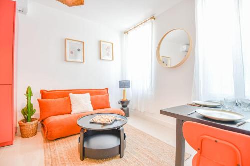 un salon avec un canapé orange et une table dans l'établissement Appart 2 ch clim proche Vieux-Port Gare St-Charles, à Marseille