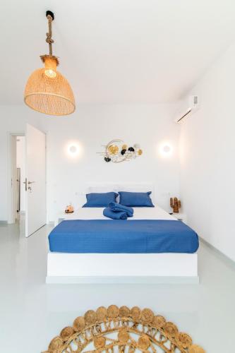 a white bedroom with a blue bed and a table at XEROLITHIA I in Agios Sostis