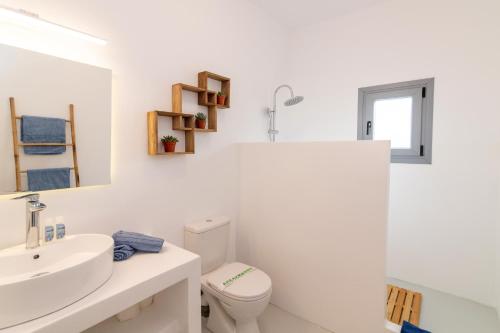 La salle de bains blanche est pourvue d'un lavabo et de toilettes. dans l'établissement XEROLITHIA I, à Agios Sostis