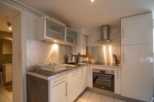 une petite cuisine avec des armoires blanches et un évier dans l'établissement Essey-St Bohème 6 pers parking apt en souplex, à Essey-lès-Nancy