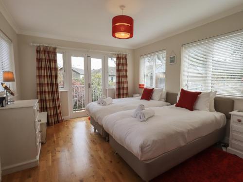 two beds in a room with windows at Silver Birches in Windermere
