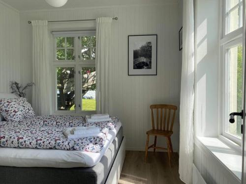 a bedroom with a bed and a chair and a window at Valldal Sentrum Overnatting in Valldal