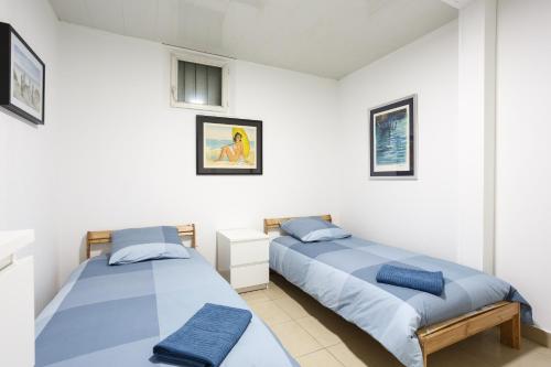 two beds in a room with white walls at F2 Osakue in Aubervilliers