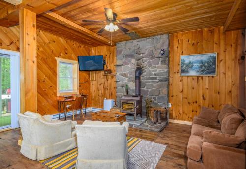 a living room with a stone fireplace and a ceiling fan at Mountain Treasure Bed and Breakfast in Maplecrest