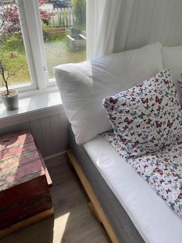 a white couch with a pillow and a window at Valldal Sentrum Overnatting in Valldal