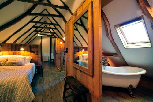 a bedroom with a bed and a tub in a room at De Schaapskooi in Hezingen