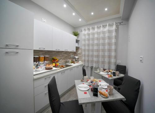 a kitchen with white cabinets and a table and chairs at B&B La Rotonda - Il Dolce Relax in Santa Maria