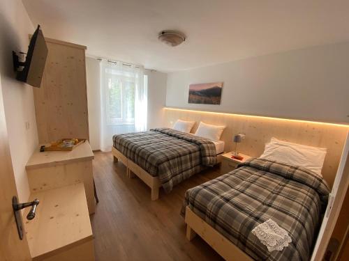 a hotel room with two beds and a window at RESIDENZA LA CANONICA in Brez