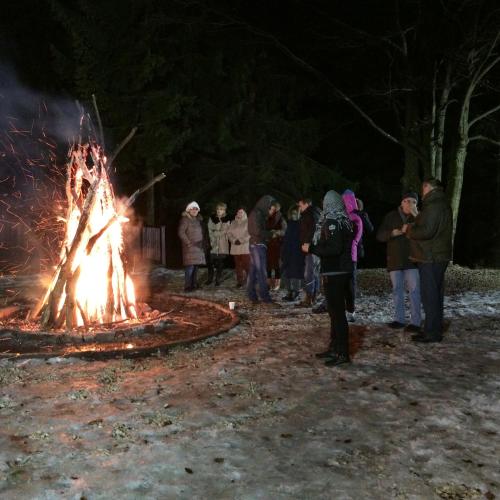 a group of people standing around a large fire at Hotel Bucegi Portile Regatului in Paraul Rece