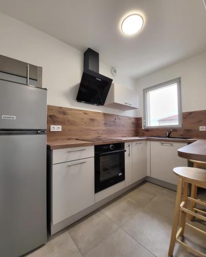 - une cuisine avec des appareils blancs et un comptoir en bois dans l'établissement Charmant type 1 neuf en hyper centre avec parking, à Corte