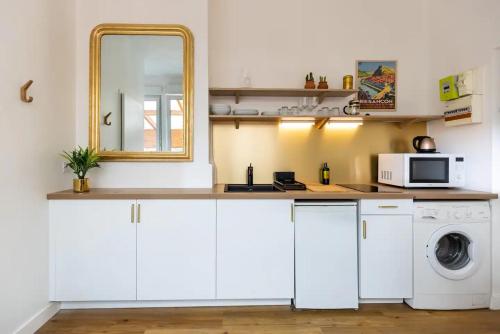 une cuisine avec des armoires blanches et une laveuse et une sécheuse dans l'établissement Le 17 Madeleine, à Besançon