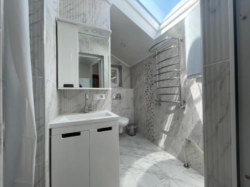 a white bathroom with a sink and a mirror at Villa aeroport розовый дом in Chişinău