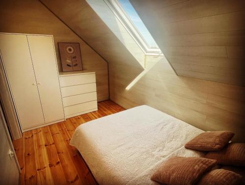 sypialnia na poddaszu z łóżkiem i oknem w obiekcie K&J Domki Letniskowe w mieście Będzino