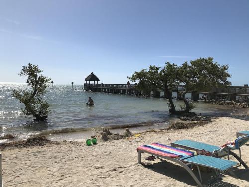 a beach with two chairs and a pier in the water at Tropical Getaway w/Private Beach 1 BD Condo in Tavernier