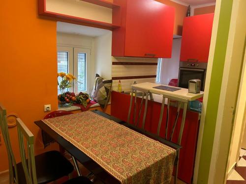 una cocina con armarios rojos y una mesa con mantel. en Apartments Bella en Kotor