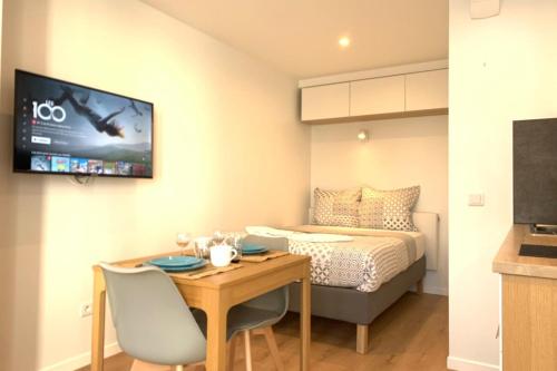 une chambre avec un lit, une table et une télévision dans l'établissement Cosy studio M1 RER BC500m Orly 20 min Netflix, à Massy