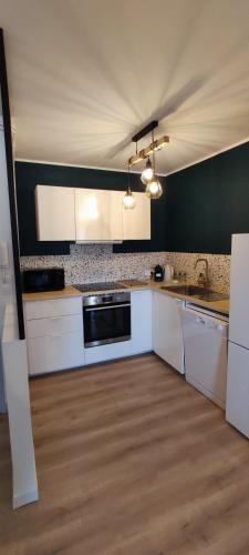 une cuisine avec des placards blancs et un mur noir dans l'établissement Avignon Intramuros - Appartement Le 36, à Avignon