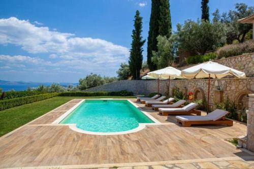 a pool with chairs and umbrellas in a backyard at Villa Artemis Nafplion in Tolo