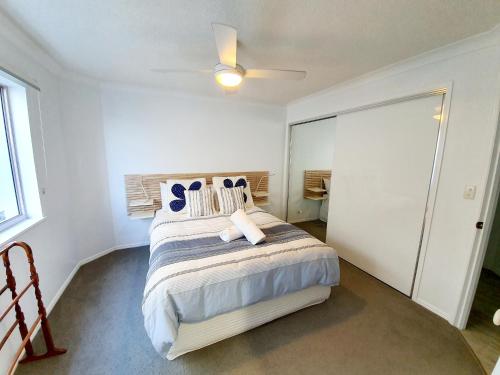 a bedroom with a large bed with a ceiling fan at Pandanus Shores Kings Beach in Caloundra