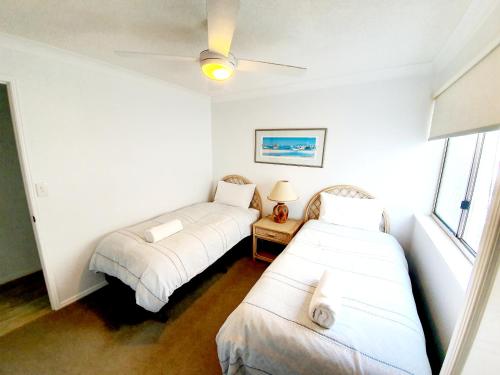 a room with two beds and a window at Pandanus Shores Kings Beach in Caloundra