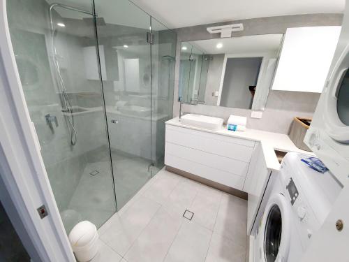 a bathroom with a shower and a washing machine at Pandanus Shores Kings Beach in Caloundra