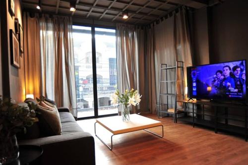 a living room with a tv and a couch and a table at STAY-DIUM House Huamark in Ban Bang Toei (1)
