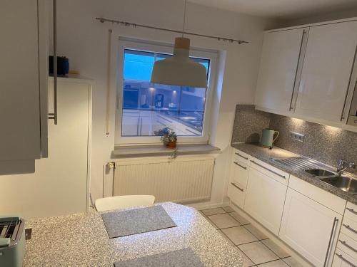 a kitchen with white cabinets and a window and a sink at Zaunkönigin in Norden